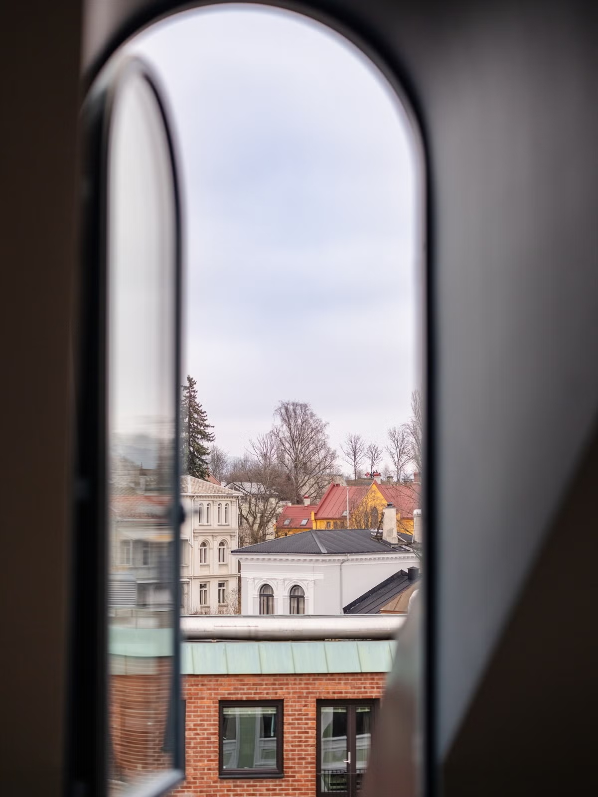 Arched attic window overlooking Oslo in the Living Under the Sky apartment by IK-architects