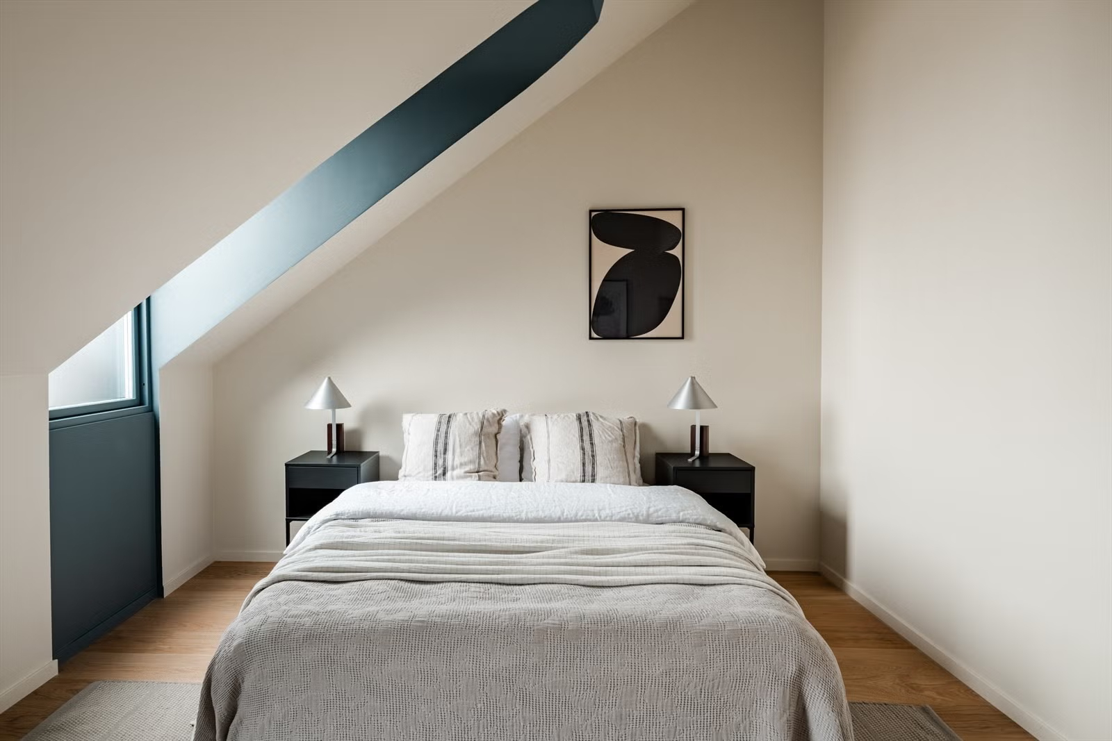 Attic bedroom beneath a sloped roof in the Living Under the Sky apartment in Oslo by IK-architects