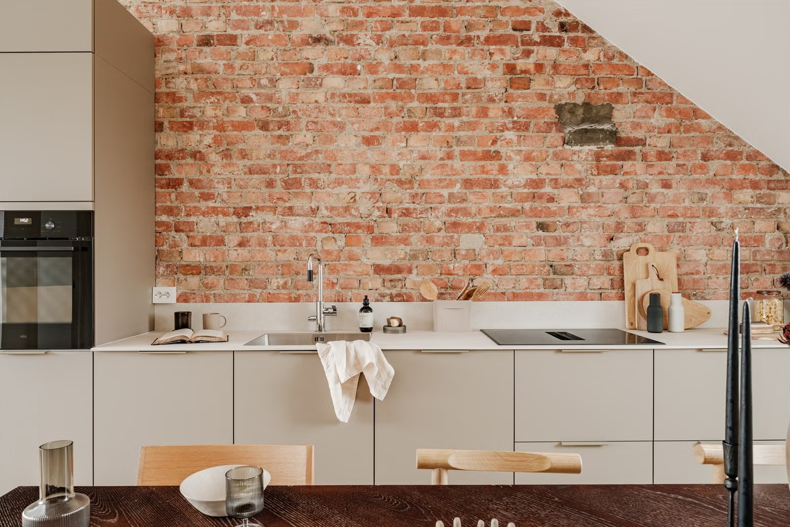 Minimal kitchen with exposed brick wall in the Living Under the Sky attic apartment in Oslo by IK-architects